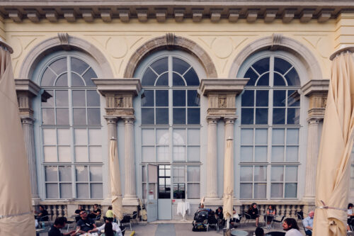 Altas ventanas en arco y columnas de piedra en la entrada del Café Gloriette.