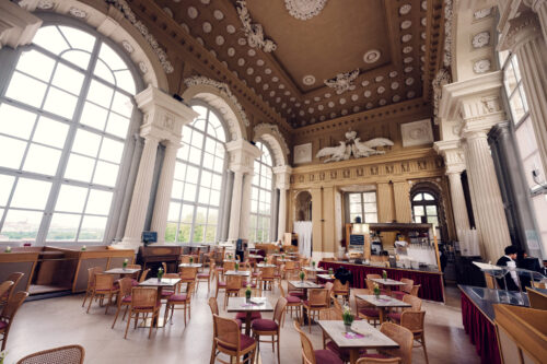 Interior del Café Gloriette visto desde un lado con grandes ventanas y zona de servicio.