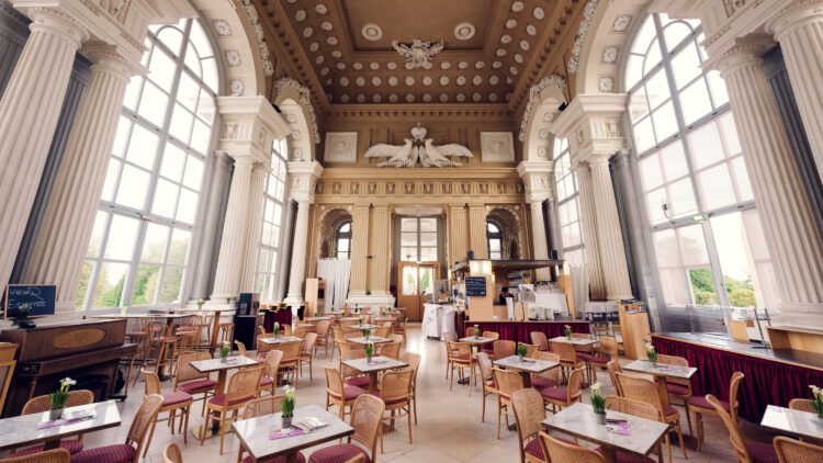 Spacious main hall of Café Gloriette with white columns and large windows overlooking Schönbrunn.
