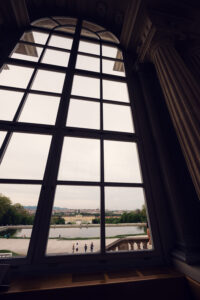 Tall arched window inside Café Gloriette framing a view of the Schönbrunn Palace grounds.