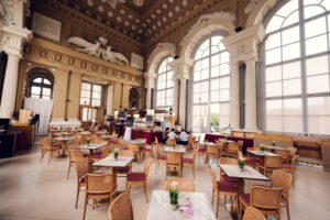 Café Gloriette interior with sculptures on the walls, large windows and tables ready for guests.