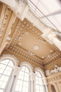 Decorated ceiling with round medallions and white sculptures inside Café Gloriette.