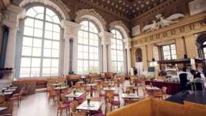 Café Gloriette dining room with set tables, high ceilings and a service counter in the back.