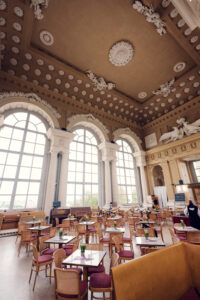 Wide view of the Café Gloriette interior with arched windows and tables set for service.