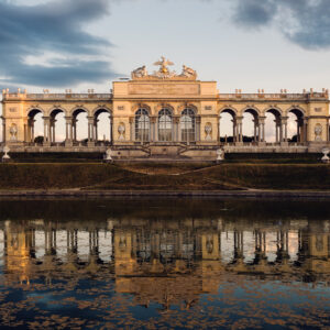 La Gloriette a Schönbrunn riflessa nello specchio d'acqua all'ora dorata.