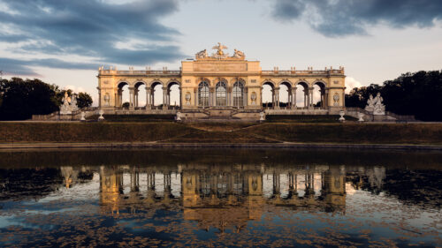 La Gloriette a Schönbrunn riflessa nello specchio d'acqua all'ora dorata.