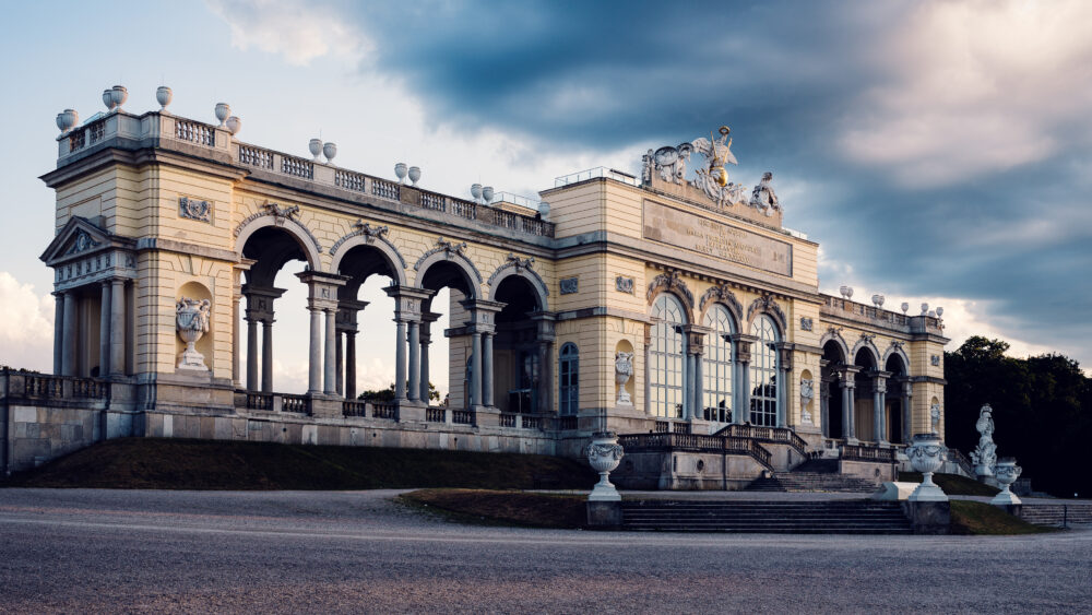 Neoclassical Gloriette structure on hill behind Schönbrunn Palace gardens.