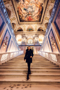 Adriana posando en la escalera principal del Museo de Historia Natural de Viena, fotografiada en los escalones de mármol.