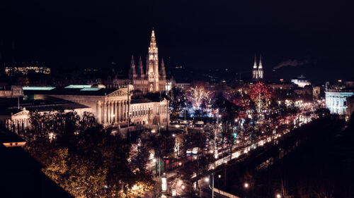 Vienna City Hall (Rathaus) illuminated at night, its Gothic architecture and spires dramatically lit against the dark sky, a landmark of Vienna's Ringstrasse.