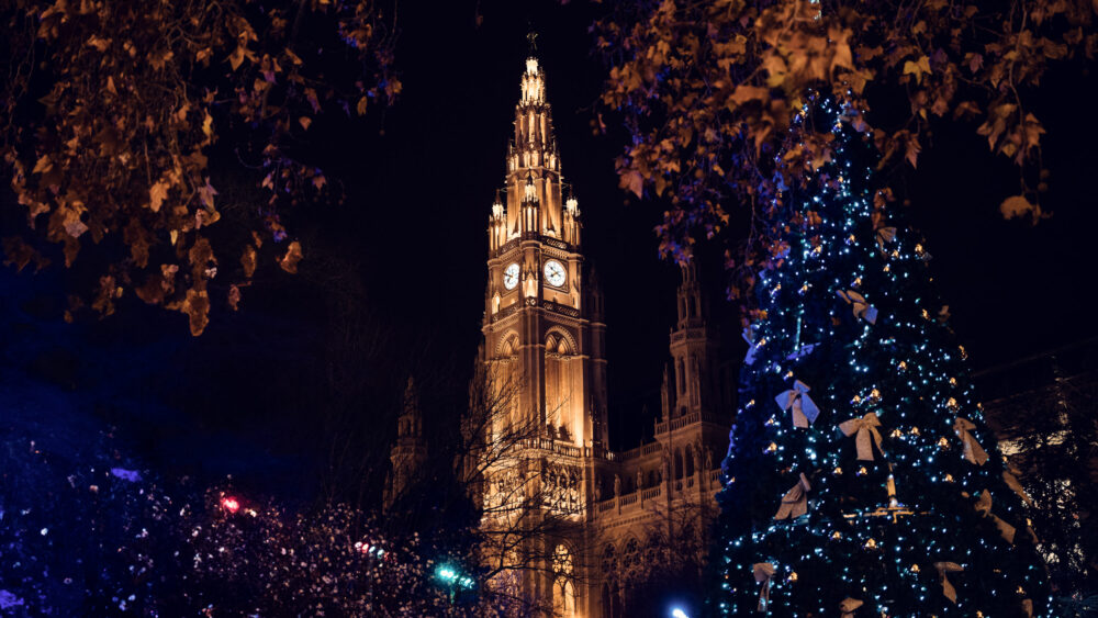 Rathaus Vienna illuminated at night, showing the detailed Gothic architecture and central tower.