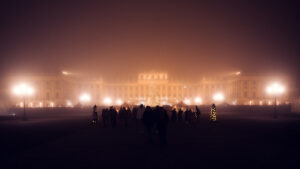 Schloss Schönbrunn in Nebel gehüllt während des Wiener Weihnachtsmarktes, barocke gelbe Fassade teilweise sichtbar durch den Dunst.
