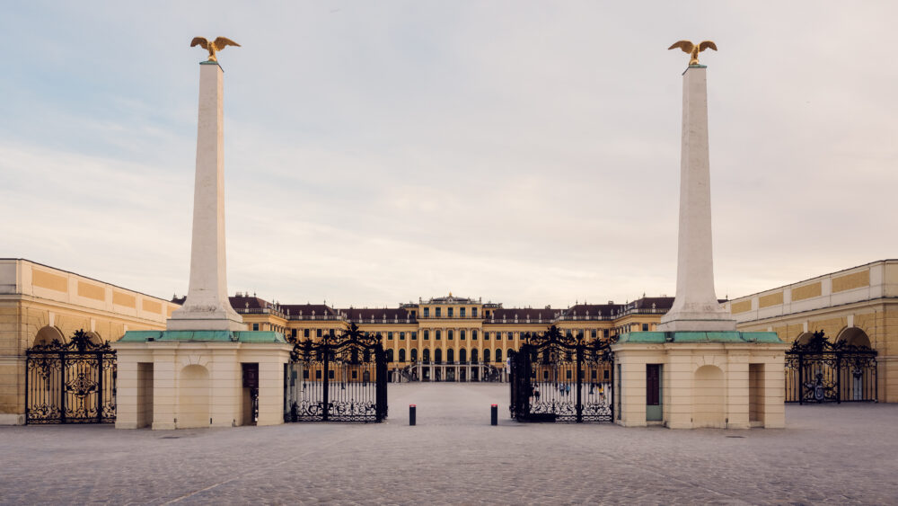 Historic entrance gate to Schönbrunn Palace, baroque Austrian imperial palace main entry with elaborate wrought iron gates and classical stone architecture.