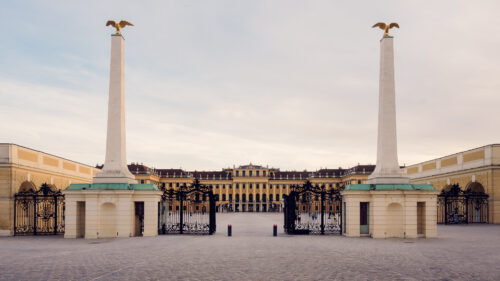 Historic entrance gate to Schönbrunn Palace, baroque Austrian imperial palace main entry with elaborate wrought iron gates and classical stone architecture.