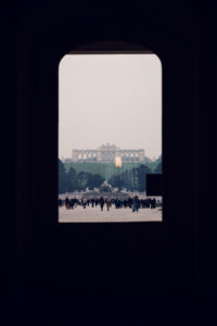 Blick auf die Gloriette vom Fenster des Schloss Schönbrunn, barocke kaiserliche Schlossgärten mit formaler Landschaftsgestaltung, die zur historischen Gloriette-Struktur führen.