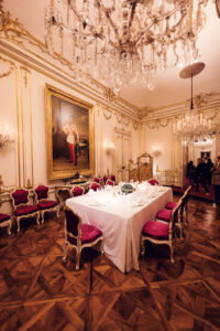 Eleganter barocker Speisesaal im Schloss Schönbrunn mit roten Samtvorhängen und kaiserlichen Möbeln.