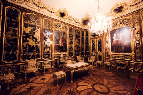 Prunkvoller Barockraum im Schloss Schönbrunn mit umfangreichen Goldverzierungen, kaiserliches Palastinterieur mit vergoldeten Rokoko-Ornamenten und Kristalllüstern.