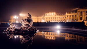 Schönbrunn Palace (Schloss Schönbrunn) illuminated during Christmas Market, baroque imperial palace with festive lighting and traditional wooden market stalls.