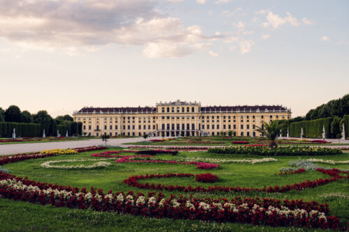 Schönbrunn Palace baroque facade with colorful flower gardens in foreground.