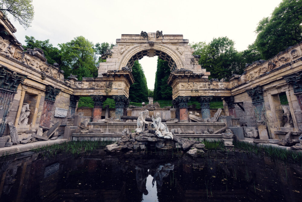 Rovine artificiali in stile romano con archi e paesaggio nel parco di Schönbrunn.