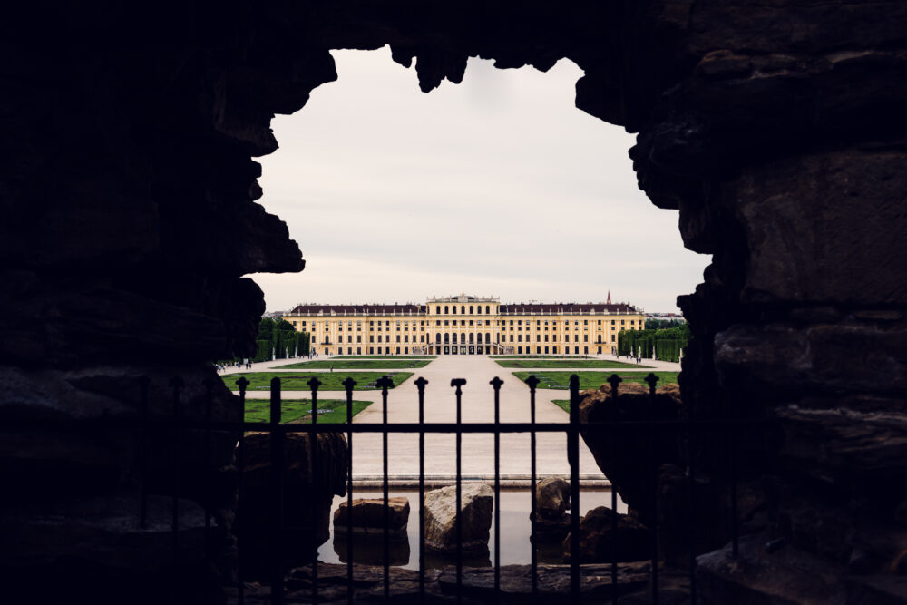 Schönbrunn Palace yellow baroque facade with formal gardens and Neptune Fountain in foreground.
