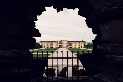 Schönbrunn Palace yellow baroque facade with formal gardens and Neptune Fountain in foreground.