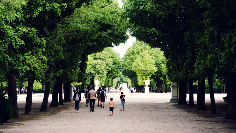 Garden pathway Schönbrunn with visitors walking on gravel walkway between formal hedge borders and palace grounds.