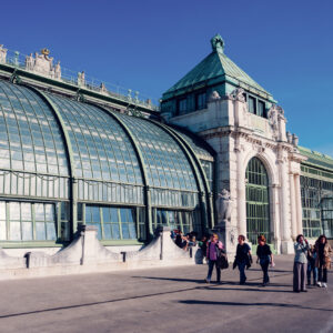 Glass and steel greenhouse building of Palmenhaus in the Burggarten with visitors outside.