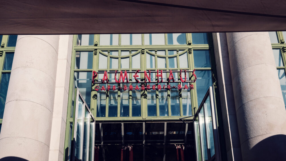 Grand entrance of Brasserie Palmenhaus, welcoming guests with its impressive architectural design.