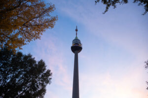 Donauturm seen from a path in Donaupark with the Danube skyline behind it.