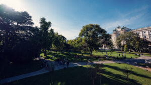 Tarde soleada en el Burggarten con visitantes descansando en el césped cerca de la Hofburg.