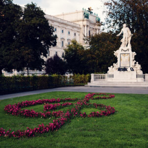 Mozart Monument in Burggarten with a treble clef flower bed in the foreground.