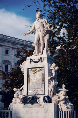 Vista completa del Monumento a Mozart en el Burggarten con la inscripción y querubines en la base.