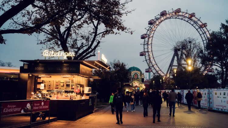 Iconic Bitzinger Würstelstand with Vienna's historic Riesenrad illuminated in the background, creating a magical evening scene.