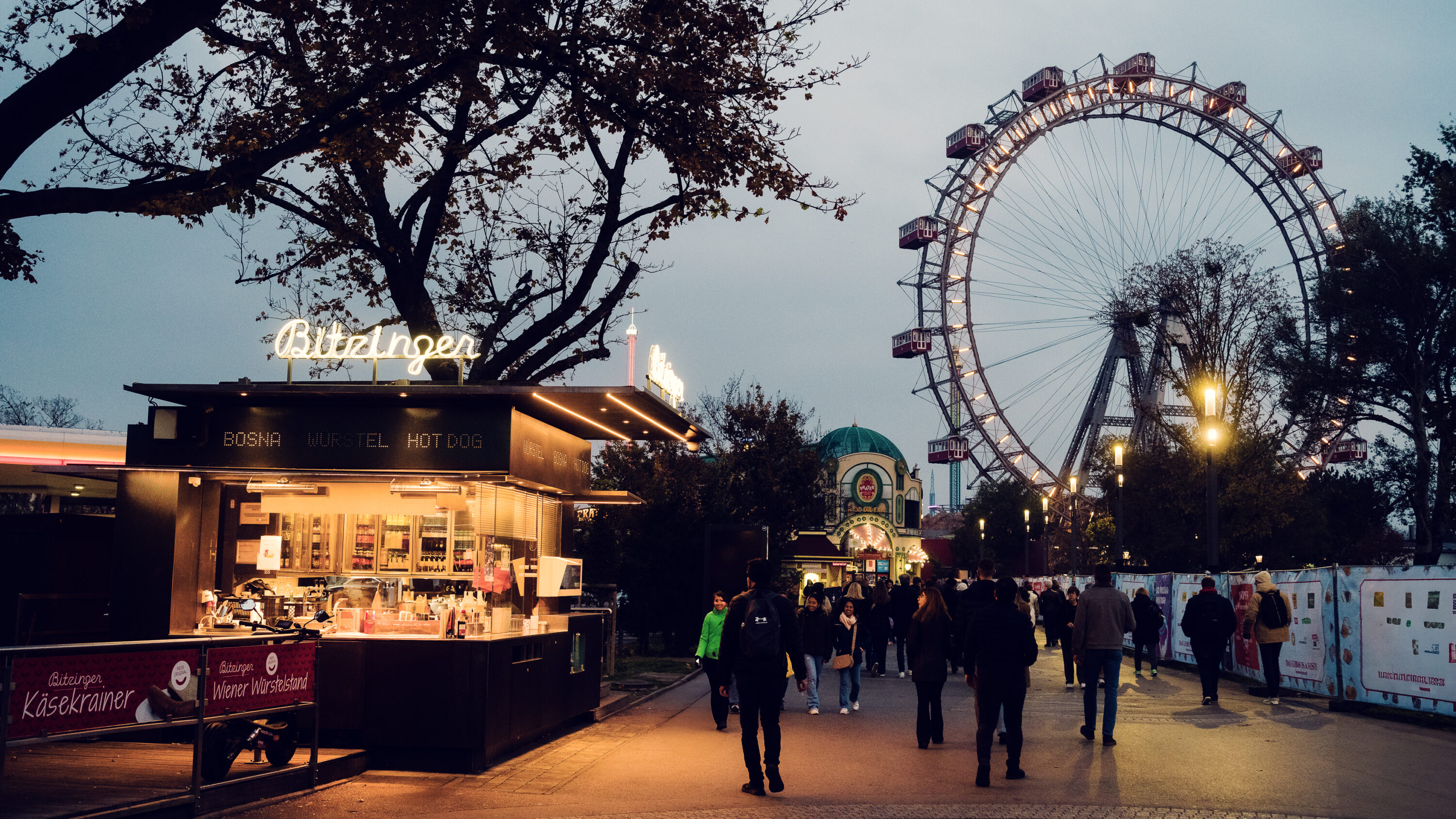 Iconic Bitzinger Würstelstand Prater with Vienna's historic Riesenrad illuminated in the background, creating a magical evening scene.