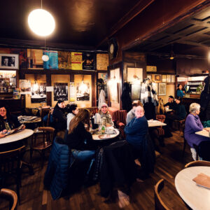 Ospiti seduti nella sala principale con pannelli di legno scuro del Café Hawelka.