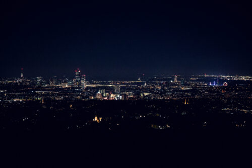 Nighttime view of Vienna from Cobenzl, with the city illuminated under a starry sky.
