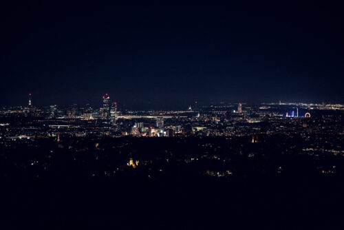 Nighttime view of Vienna from Cobenzl, with the city illuminated under a starry sky.