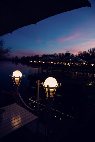 Dinner tables on the Das Bootshaus terrace at sunset along the Alte Donau.