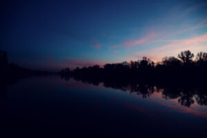 Das Bootshaus terrace during sunset with the sky reflected in the water.