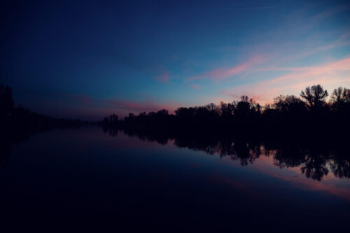 Das Bootshaus terrace during sunset with the sky reflected in the water.