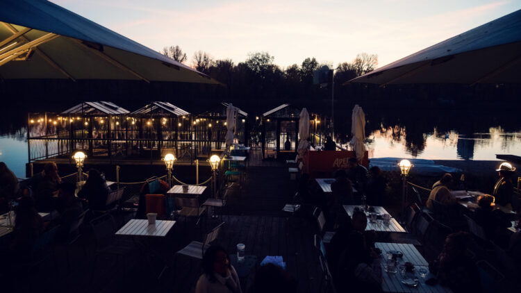 Dinner table on the Das Bootshaus terrace with the Alte Donau waterfront in the background.