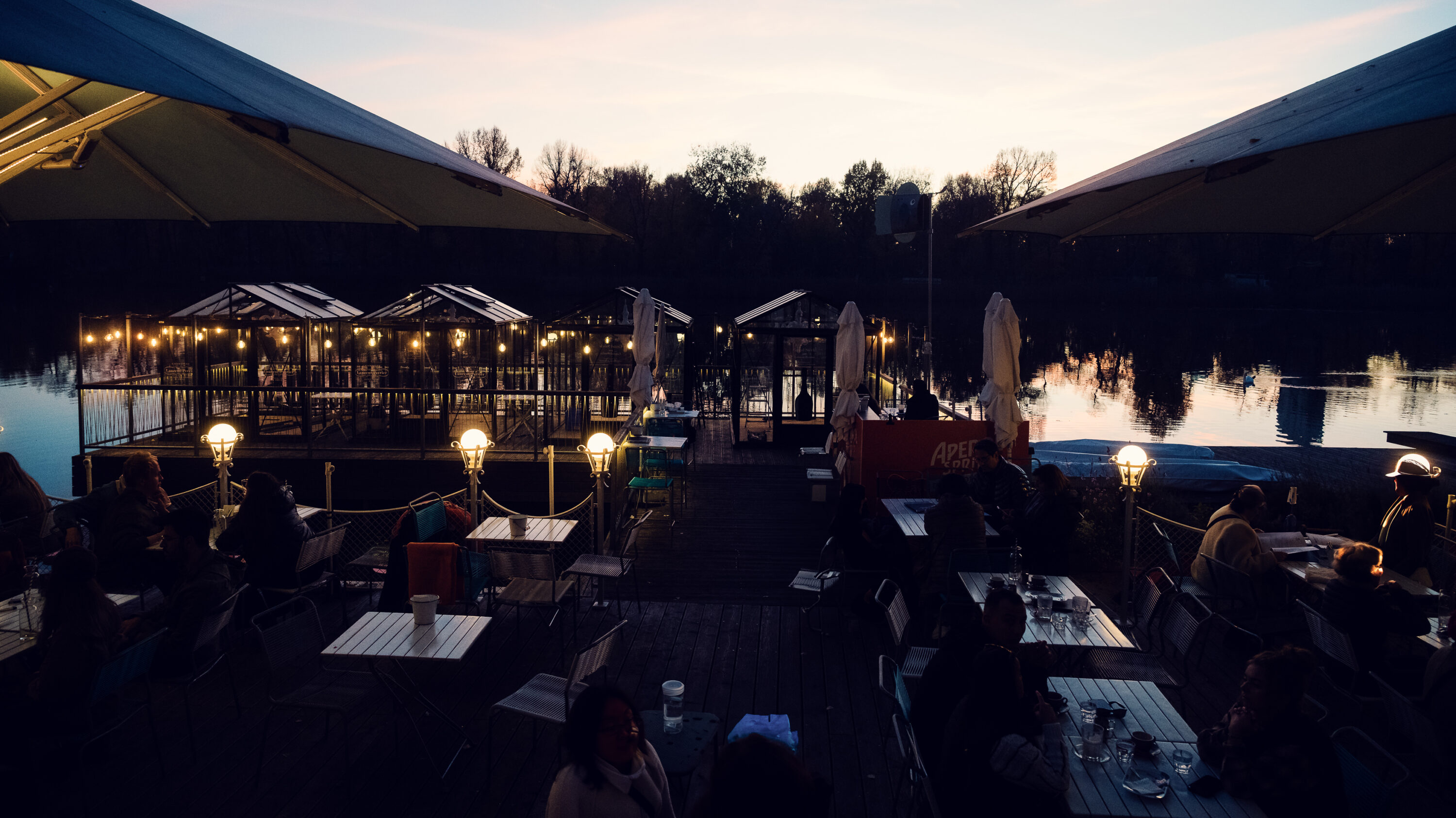 Exclusive dinner setting on Das Bootshaus terrace, framed by modern architecture and natural waterscape.
