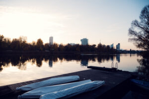 Wooden pier stretching into the Alte Donau with Das Bootshaus and the Vienna skyline behind it.