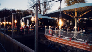 String lights above the Das Bootshaus terrace at night, reflected in the water.