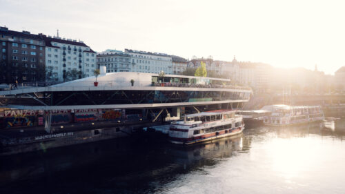 Motto am Fluss' distinctive ship-like architecture gleaming in the sunlight, perfectly positioned along Vienna's Danube Canal.