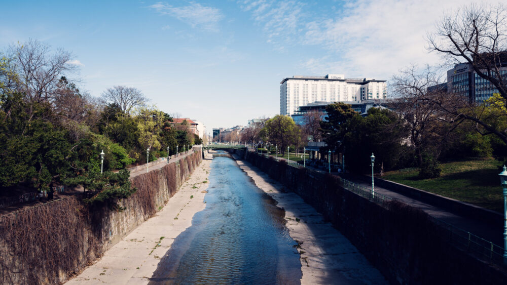 Meandering Wienfluss through Stadtpark, creating romantic water features and stone bridges.