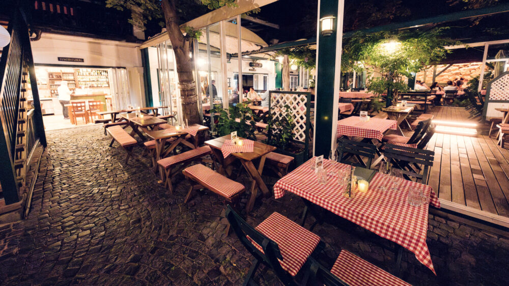 Vintage lanterns at Martin Sepp cast warm light across traditional checkered tablecloths.