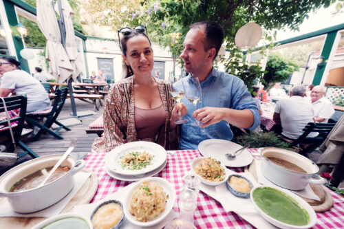 Romantic couple toasting with glasses of Gemischter Satz wine, framed by traditional Heuriger decor.