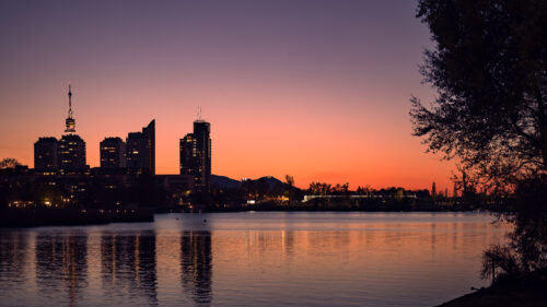 Sonnenuntergang über der Wiener Stadtsilhouette von der Alten Donau mit goldenem Abendlicht.