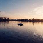 Boot auf der Alten Donau in der Abenddämmerung mit der im Hintergrund leuchtenden Wiener Stadtsilhouette.